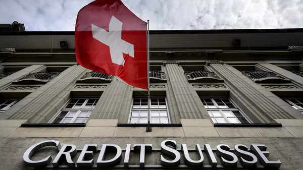 Флаг Швейцарии над вывеской банка Credit Suisse в Берне