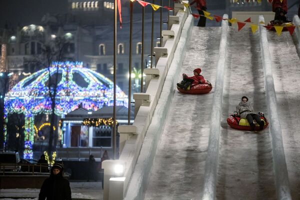 Дети катаются на ледяной горке на площади Революции в Москве Дети катаются на ледяной горке на площади Революции в Москве