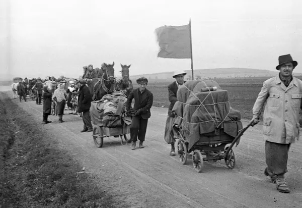 Беженцы везут по дороге тележки со скарбом. В районе Вены. 1945 год 