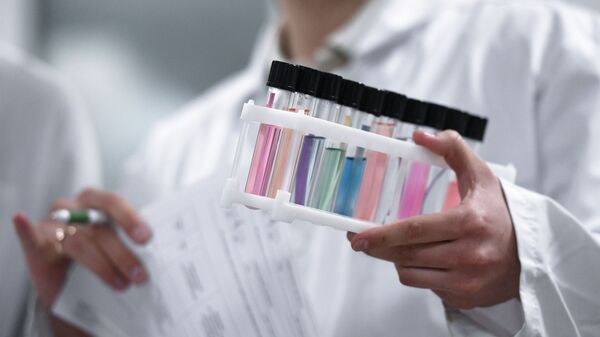 Сотрудник держит пробирки с пробами в Национальной антидопинговой лаборатории