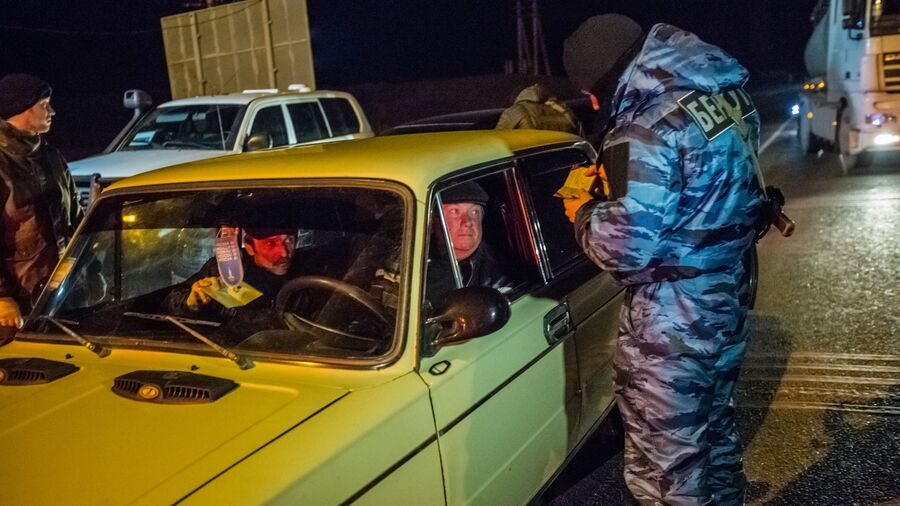 Сотрудник подразделения милиции специального назначения Беркут проверяет документы на блокпосту на въезде в Крым в районе Армянска Сотрудник подразделения милиции специального назначения Беркут проверяет документы на блокпосту на въезде в Крым в районе Армянска