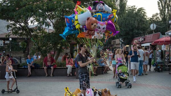 Отдыхающие на набережной Черного моря в Коктебеле Отдыхающие на набережной Черного моря в Коктебеле