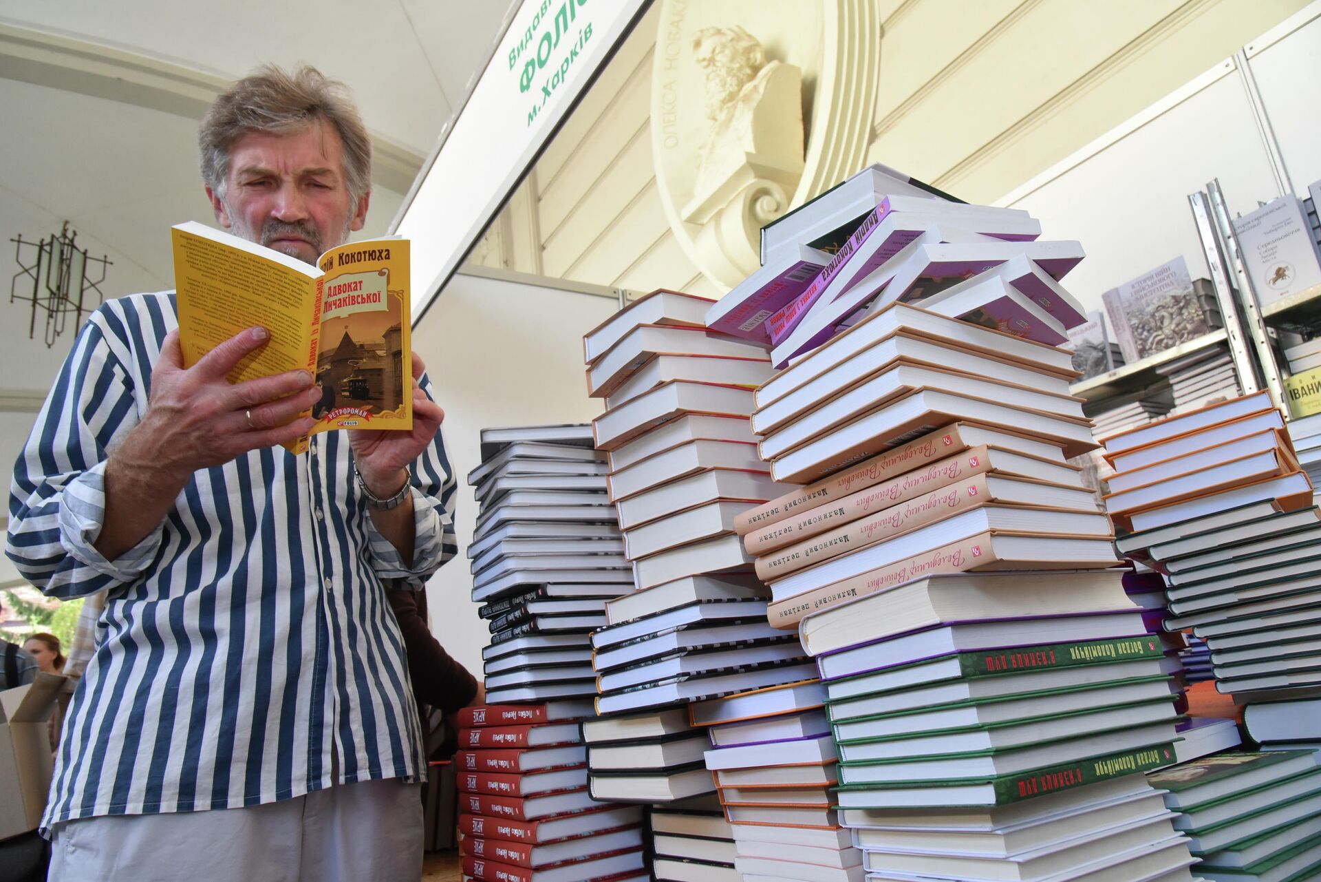 Посетитель читает книгу на книжной ярмарке во Львове Посетитель читает книгу на книжной ярмарке во Львове - РИА Новости, 1920, 25.09.2020