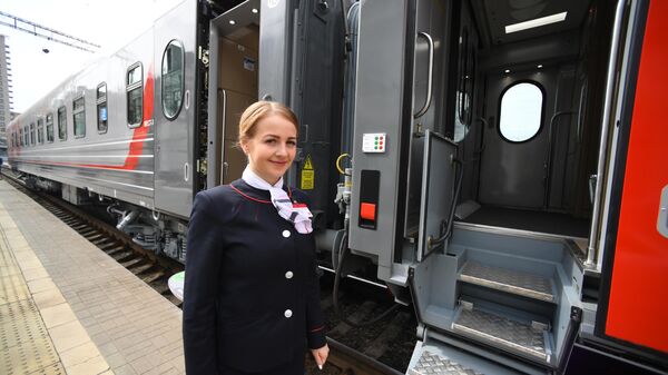 Проводница возле нового одноэтажного купейного вагона дальнего следования на Рижском вокзале в Москве Проводница возле нового одноэтажного купейного вагона дальнего следования на Рижском вокзале в Москве