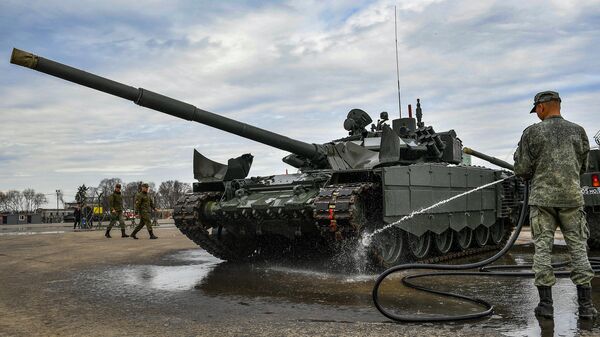 Военнослужащий моет танк Т-72, который примет участие в параде Победы на Красной площади 9 мая