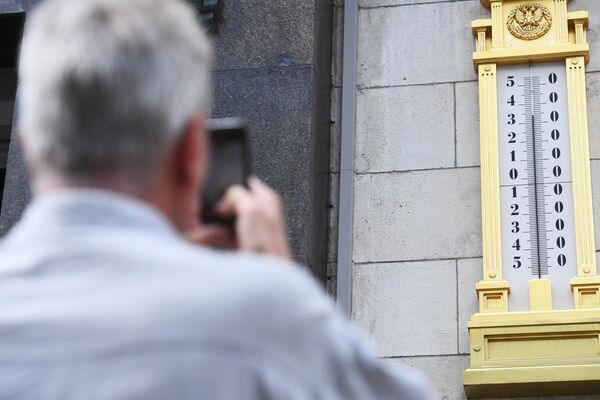 Мужчина фотографирует термометр на здании Государственной Думы РФ в Москве Мужчина фотографирует термометр на здании Государственной Думы РФ в Москве