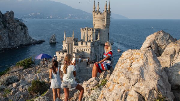 Отдыхающие фотографируются возле замка Ласточкино гнездо на береговой скале в поселке Гаспра в Крыму