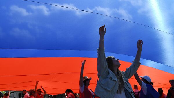 Участники флешмоба в честь Дня государственного флага России на проспекте Сахарова в Москве Участники флешмоба в честь Дня государственного флага России на проспекте Сахарова в Москве