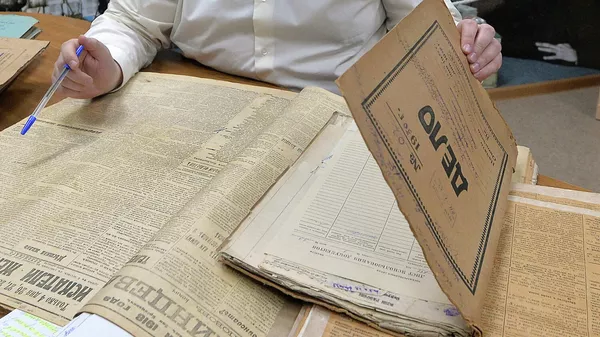 Сотрудник разбирает папки с документами в Государственном архиве