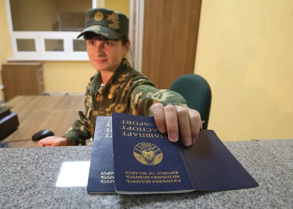 Пограничник проверяет паспорта на пограничном переходе между Белоруссией и Польшей Переров Пограничник проверяет паспорта на пограничном переходе между Белоруссией и Польшей Переров