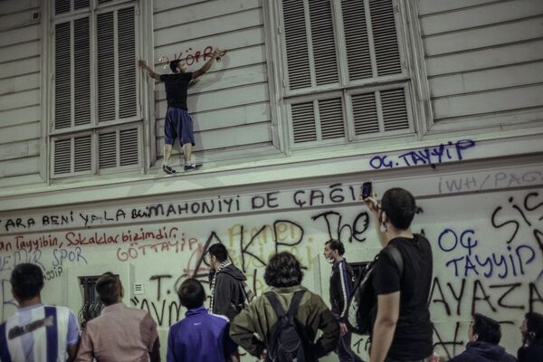 Один из протестующих на стене здания во время столкновения с сотрудниками полиции в Стамбуле Один из протестующих на стене здания во время столкновения с сотрудниками полиции в Стамбуле