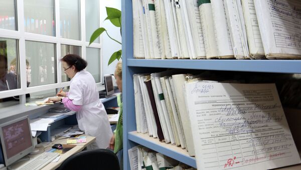 Медицинский работник выдает медицинскую карту пациенту в регистратуре районной поликлиники Медицинский работник выдает медицинскую карту пациенту в регистратуре районной поликлиники